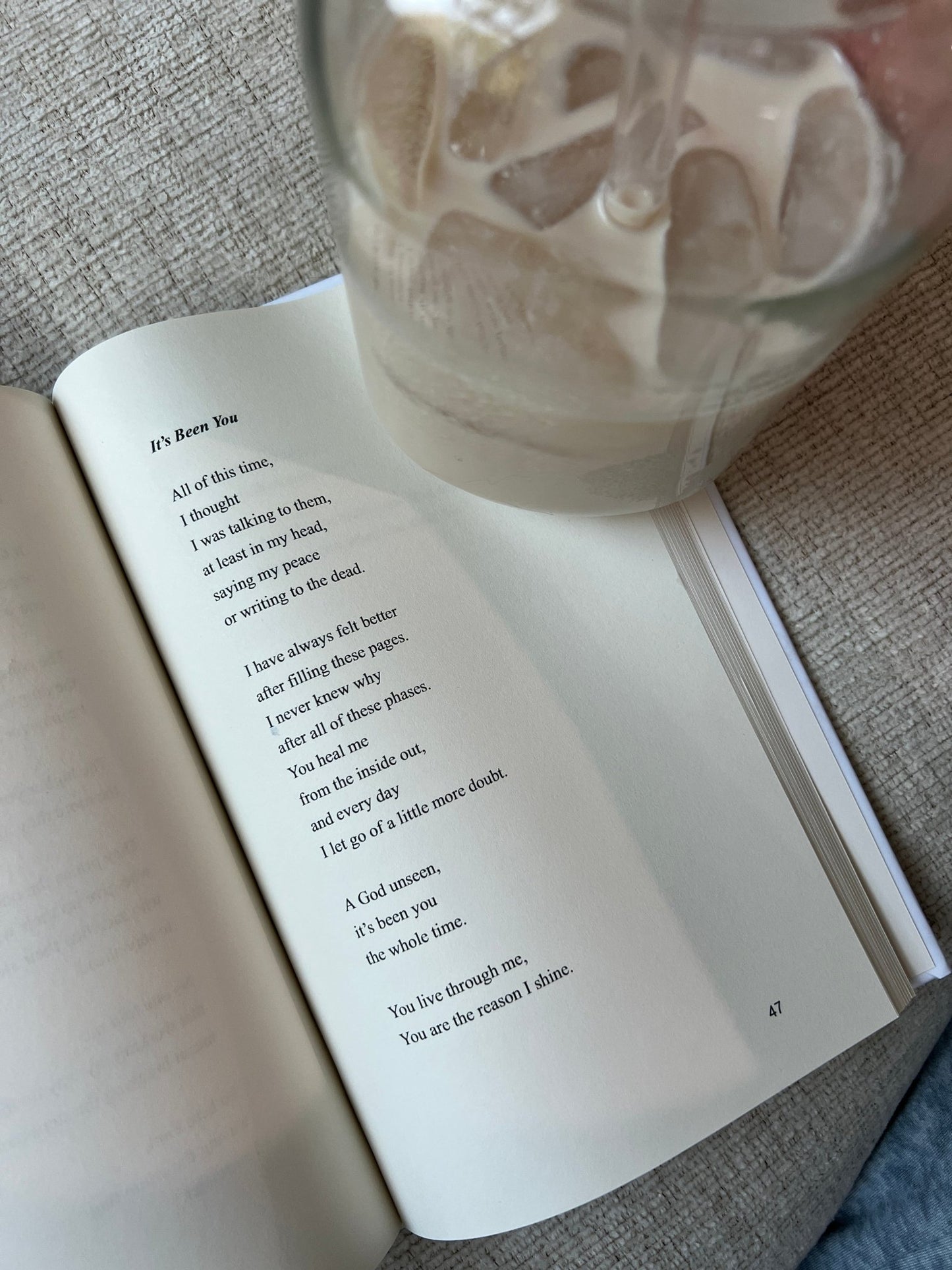 Open book on a textured surface with a glass of water nearby